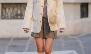 Elegancka stylizacja z kratowaną spódnicą plisowaną, kremową marynarką i futrzaną torebką.