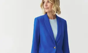 Kobieta w niebieskiej marynarce i jasnoniebieskiej bluzce, patrząca w bok.