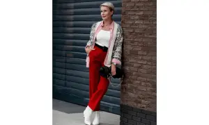 Kobieta w czerwonych spodniach i białej bluzce z czerwonymi pasami, narzucony wzorzysty kardigan. Idealna stylizacja: jaka bluzka do czerwonych spodni.