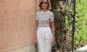 Elegancka kobieta w białych spodniach i pasiastym topie, idealna stylizacja na lato.