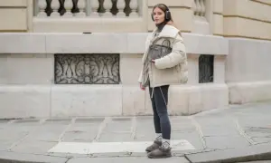 Modna dziewczyna w słuchawkach prezentuje stylowe stylizacje ze skarpetkami, które dodają charakteru jej zimowemu outfitowi.