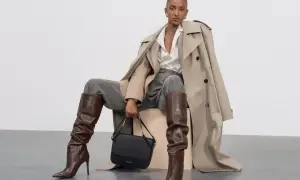 Elegancka stylizacja: jak nosić koszulę oversize z trenczem, szarymi spodniami i brązowymi kozakami.