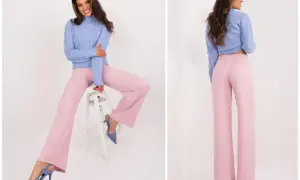 Uśmiechnięta modelka w granatowym sweterku i pudrowy róż stylizacje – szerokie spodnie i szpilki.