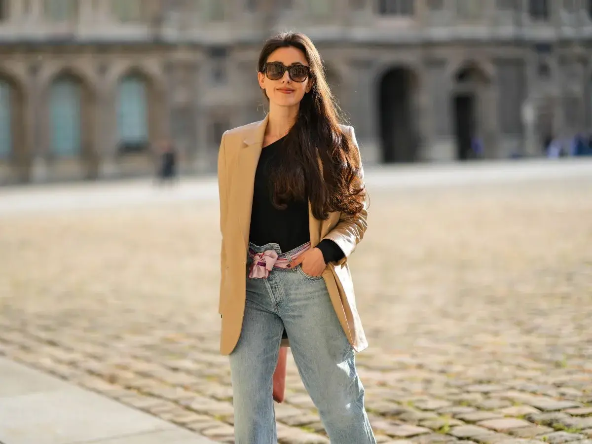 Stylowa kobieta w beżowej marynarce i jeansach mom fit. Jej stylizacje to kwintesencja miejskiego szyku.