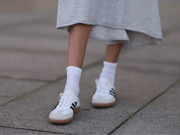 Białe Adidas Samba w stylizacjach z szarą spódnicą i białymi skarpetkami. Klasyka, która zawsze się obroni.