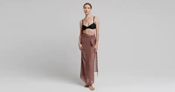 Modelka prezentuje, jak wiązać pareo w elegancki sposób. Długi, brązowy materiał owinięty wokół bioder, z ozdobnym węzłem.